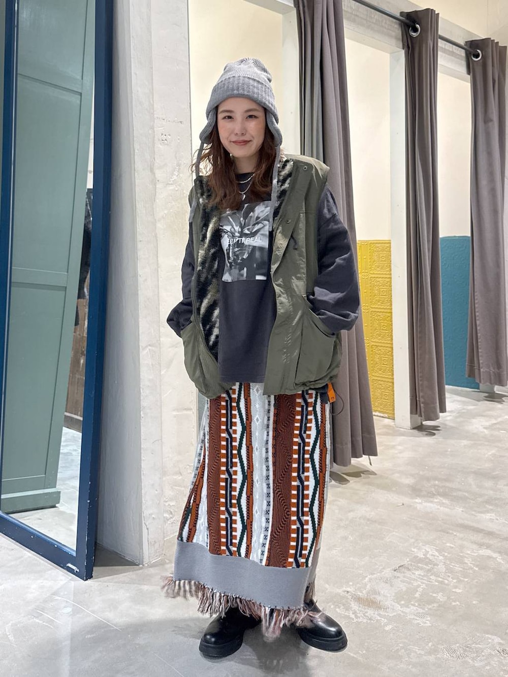 グリーン系のベスト、ブラック系のブーツを着用したレディースの秋コーディネートの3枚目の写真