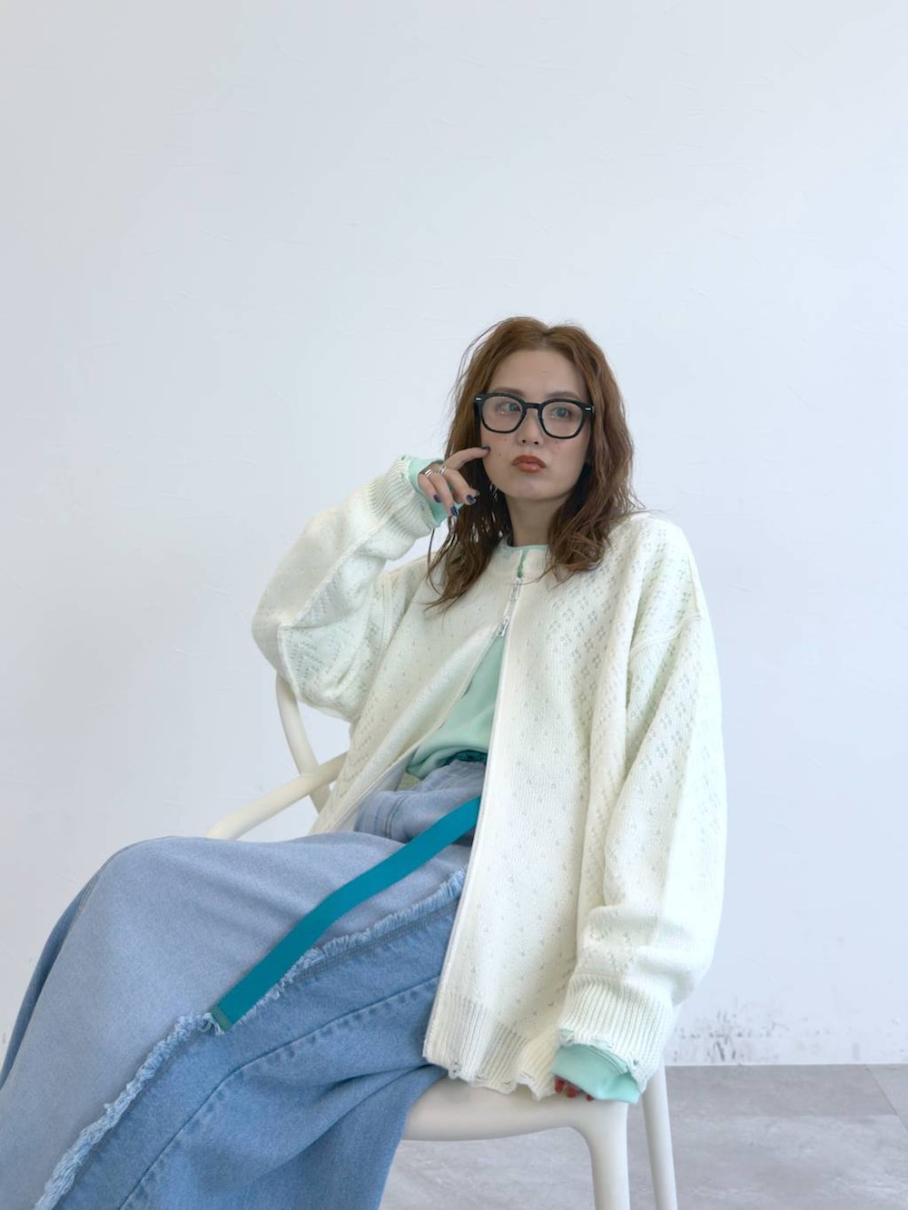 ブルー系のデニムスカート、ホワイト系のブルゾン、グリーン系のTシャツ/カットソーを着用したレディースの冬コーディネートの3枚目の写真