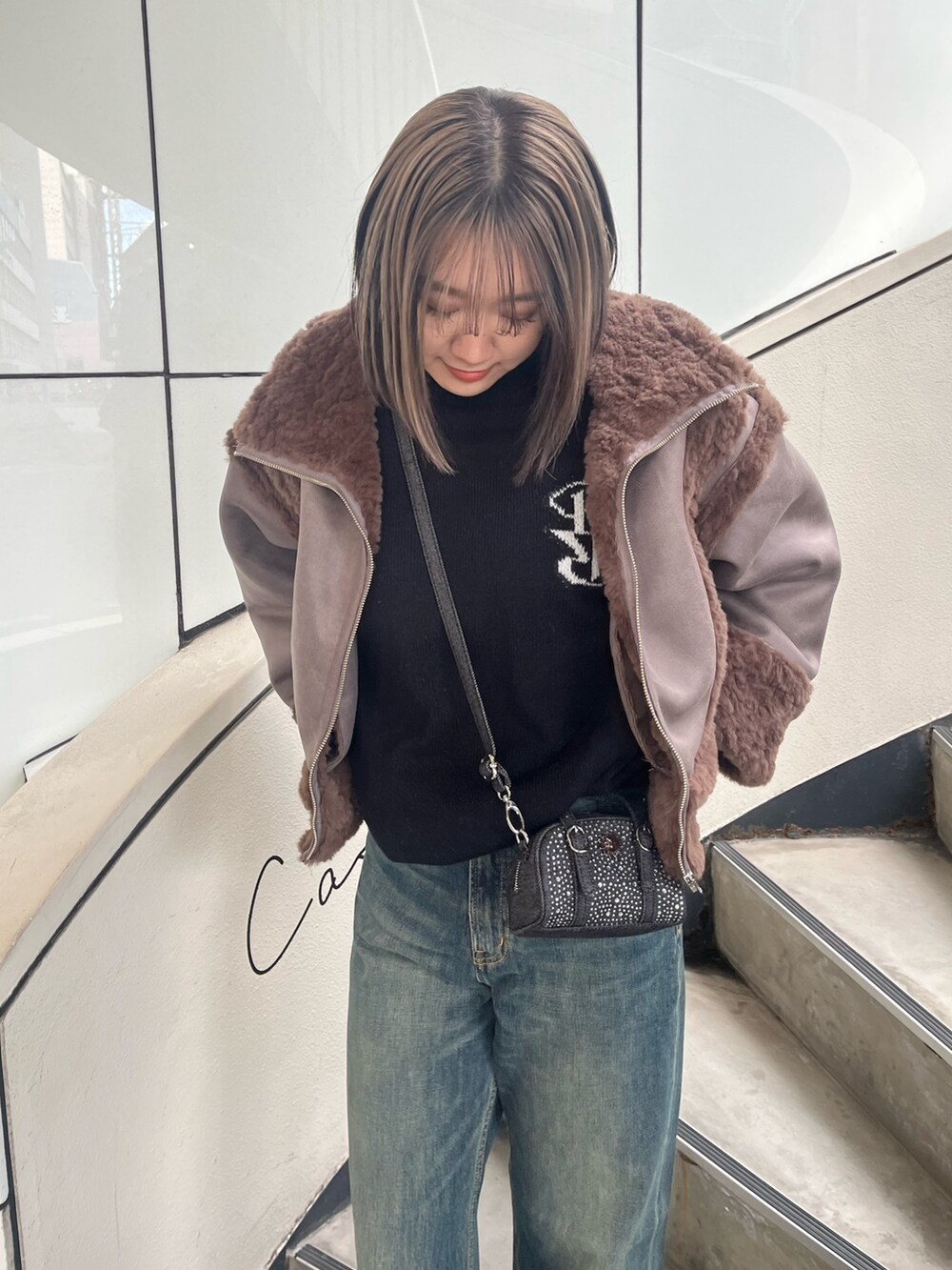 ブラウン系のムートンコート、ホワイト系のニット/セーター、ブルー系のデニムパンツを着用したレディースの冬コーディネートの3枚目の写真