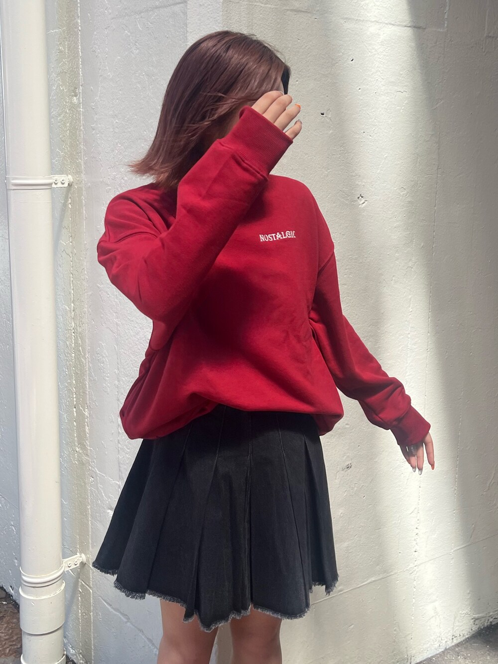 ブラック系のデニムスカート、レッド系のスウェット、ブラック系のブーツを着用したレディースの秋コーディネートの5枚目の写真