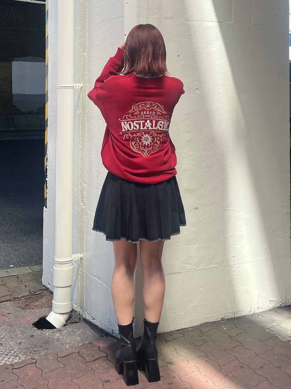 ブラック系のデニムスカート、レッド系のスウェット、ブラック系のブーツを着用したレディースの秋コーディネートの3枚目の写真