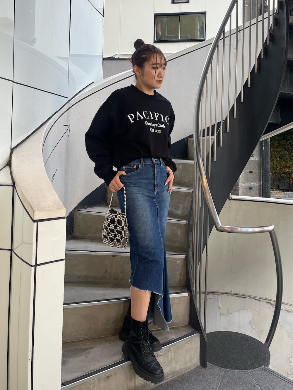 ブラック系のブーツ、ブラック系のスウェット、ブルー系のデニムスカートを着用したレディースの冬コーディネートの2枚目の写真