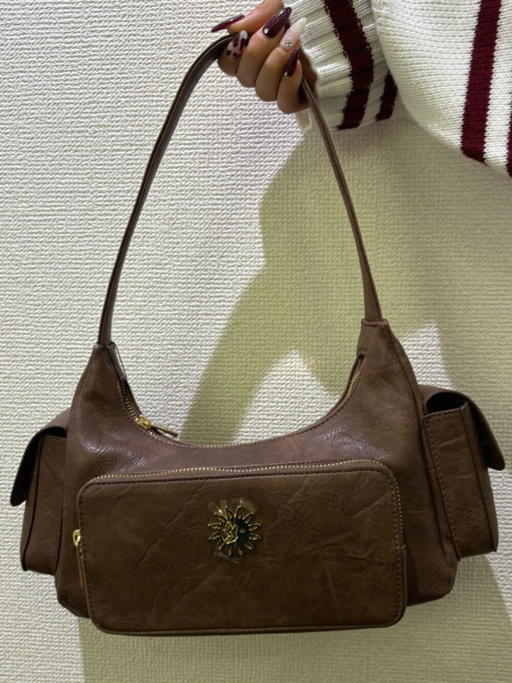 ブルー系のデニムパンツ、ブラウン系のハンドバッグ、ホワイト系のニット/セーターを着用したレディースの冬コーディネートの7枚目の写真