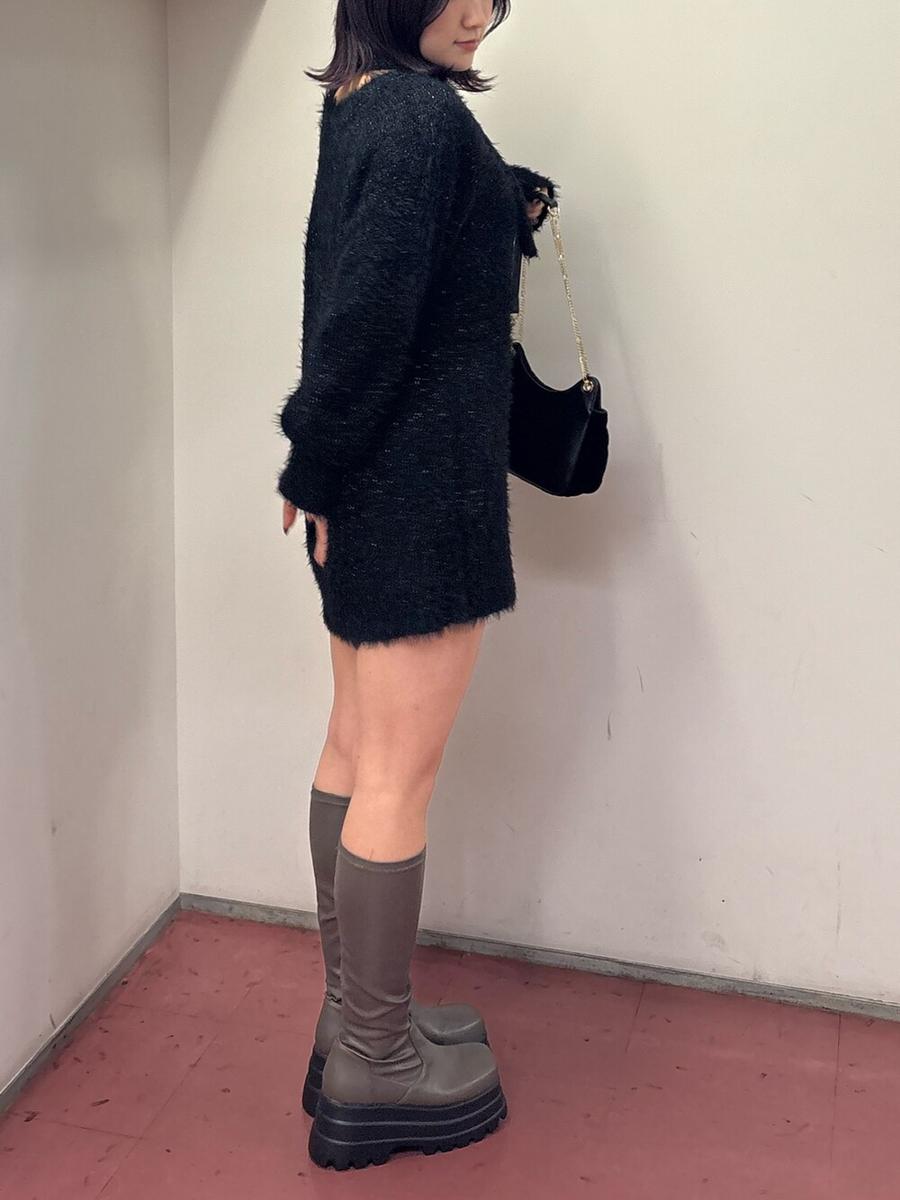 ブラック系のワンピース、ブラック系のショルダーバッグ、グリーン系のブーツを着用したレディースの冬コーディネートの2枚目の写真