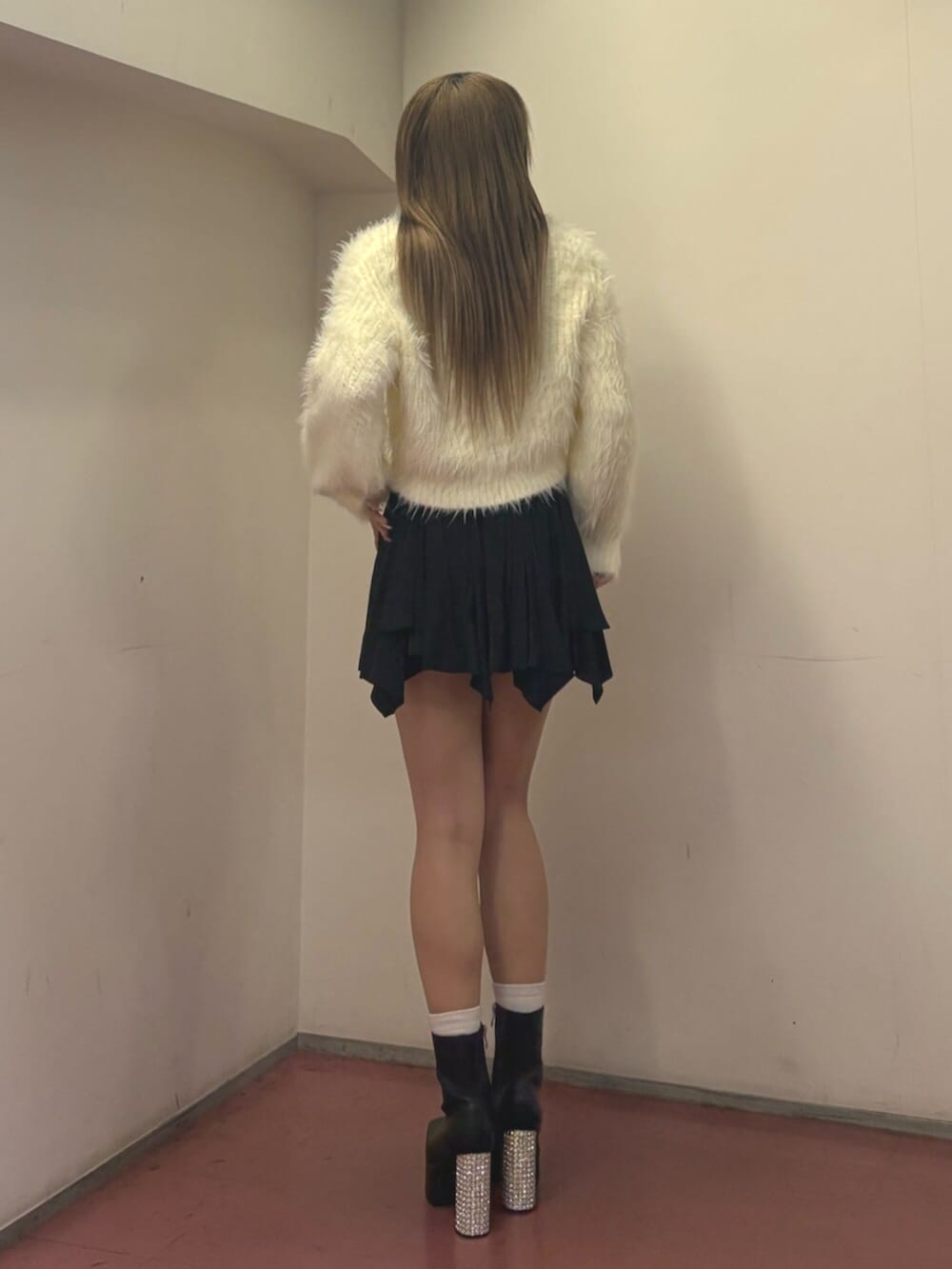 ブラック系のブーツ、ホワイト系のニット/セーター、ブラック系のスカートを着用したレディースの冬コーディネートの3枚目の写真