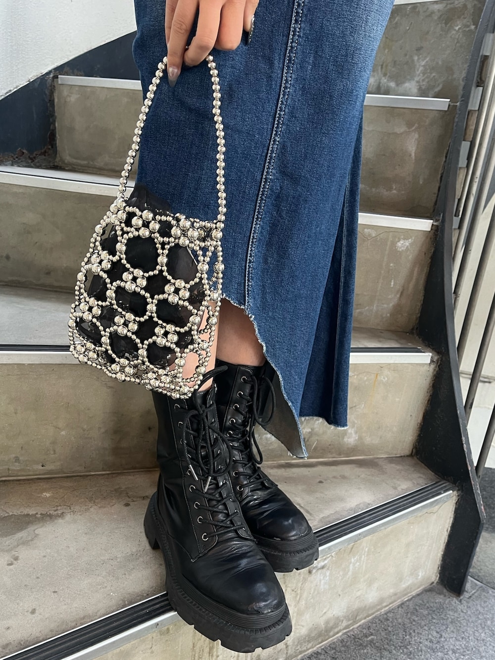 ブラック系のブーツ、ブラック系のスウェット、ブルー系のデニムスカートを着用したレディースの冬コーディネートの5枚目の写真