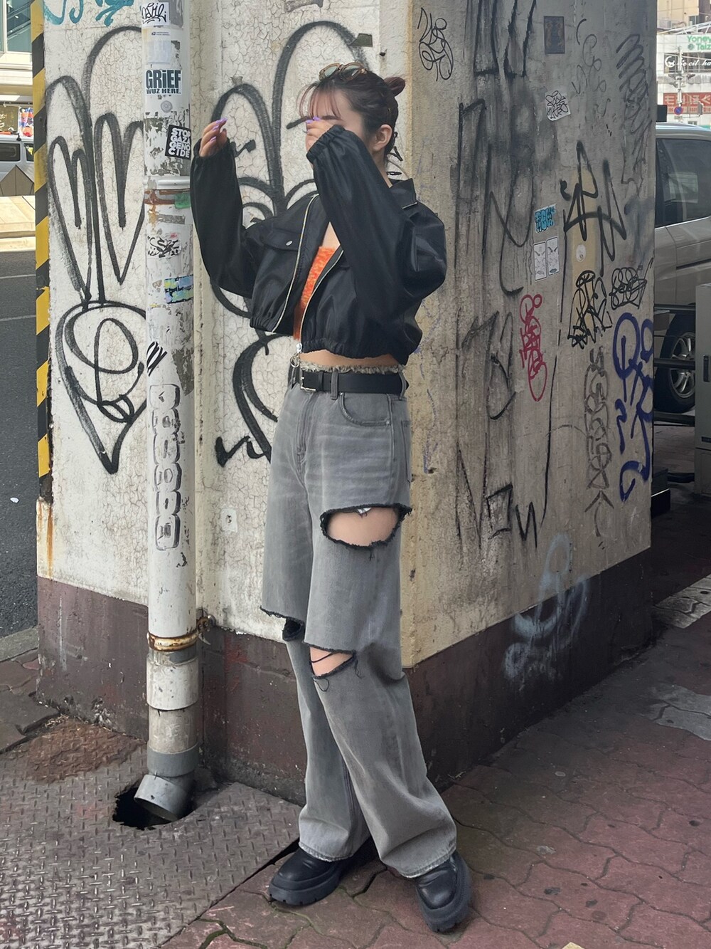 ブラック系のデニムパンツ、ブラック系のブーツ、オレンジ系のニット/セーターを着用したレディースの冬コーディネートの2枚目の写真