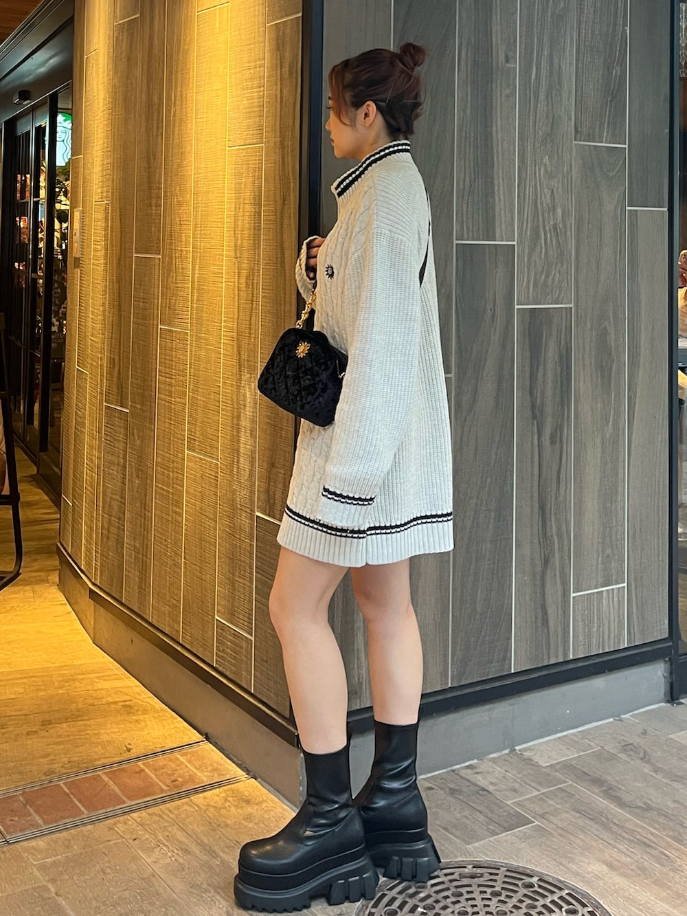 グレー系のニット/セーター、ブラック系のショルダーバッグ、ブラック系のブーツを着用したレディースの秋コーディネートの4枚目の写真