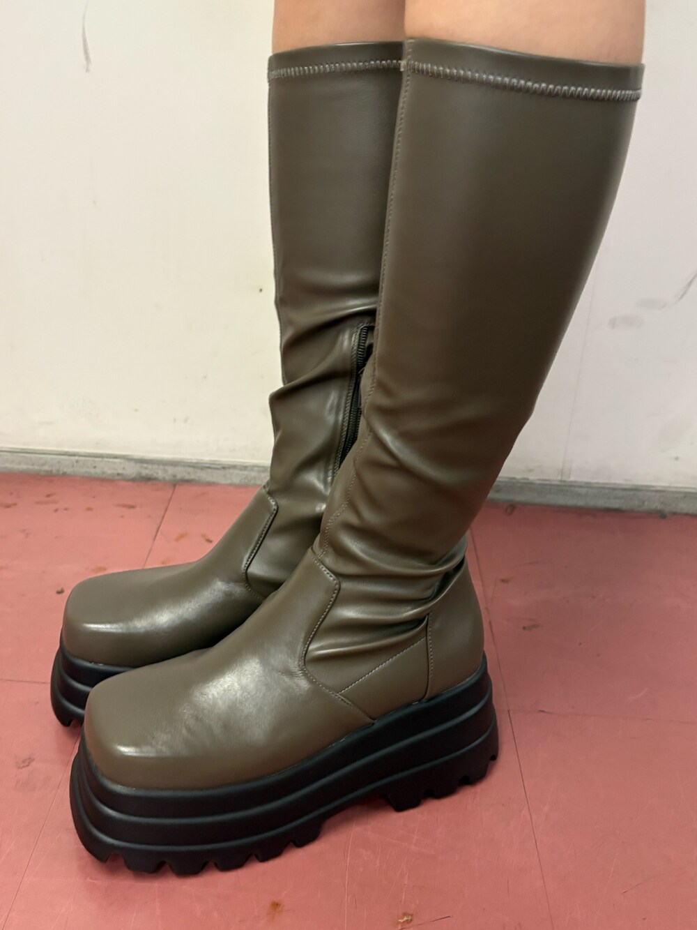 ブラック系のワンピース、ブラック系のショルダーバッグ、グリーン系のブーツを着用したレディースの冬コーディネートの6枚目の写真