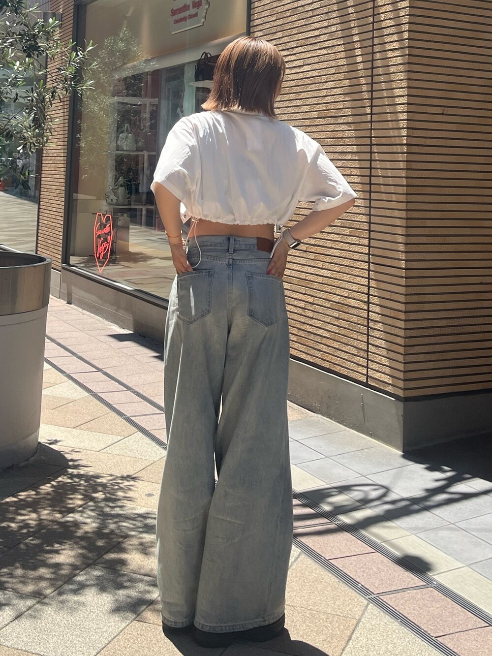 ブルー系のデニムパンツ、ブラック系のサンダル、ブルー系のキャミソールを着用したレディースの夏コーディネートの4枚目の写真