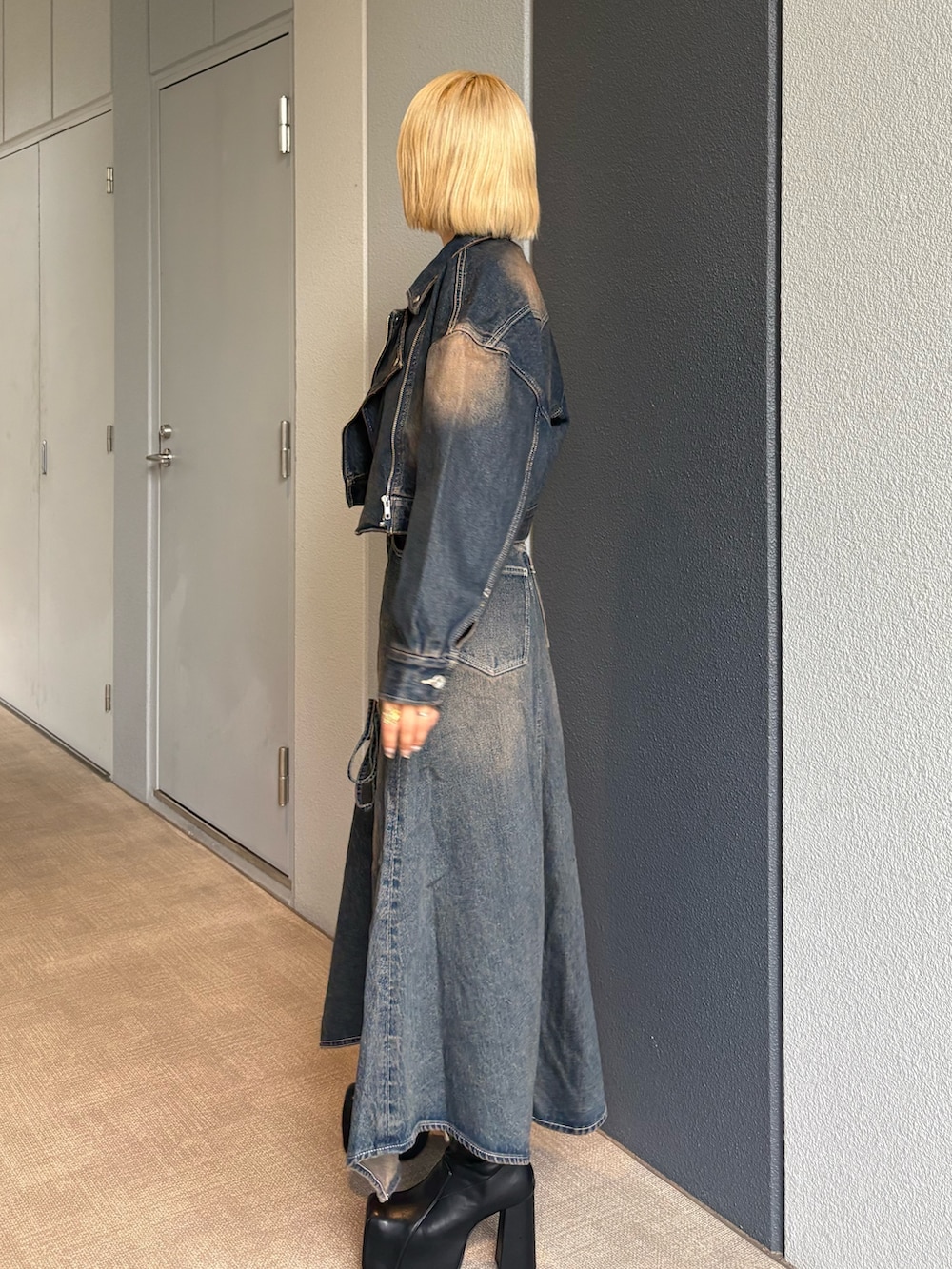 ブルー系のデニムジャケット、ブルー系のデニムスカート、ブラック系のブーツを着用したレディースの秋コーディネートの3枚目の写真