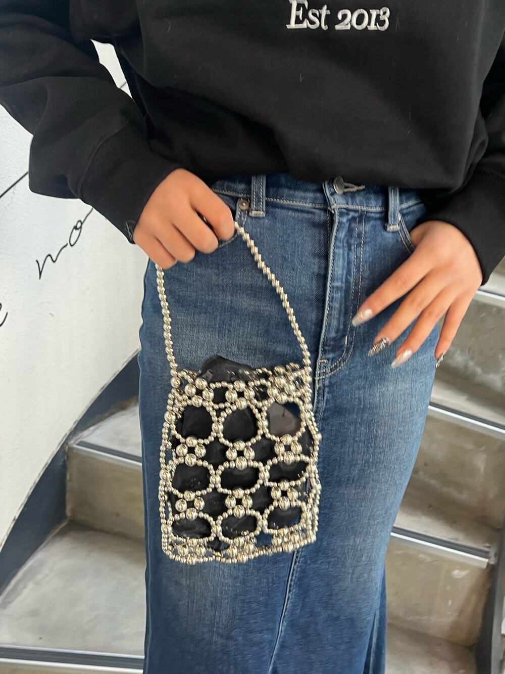 ブラック系のブーツ、ブラック系のスウェット、ブルー系のデニムスカートを着用したレディースの冬コーディネートの4枚目の写真