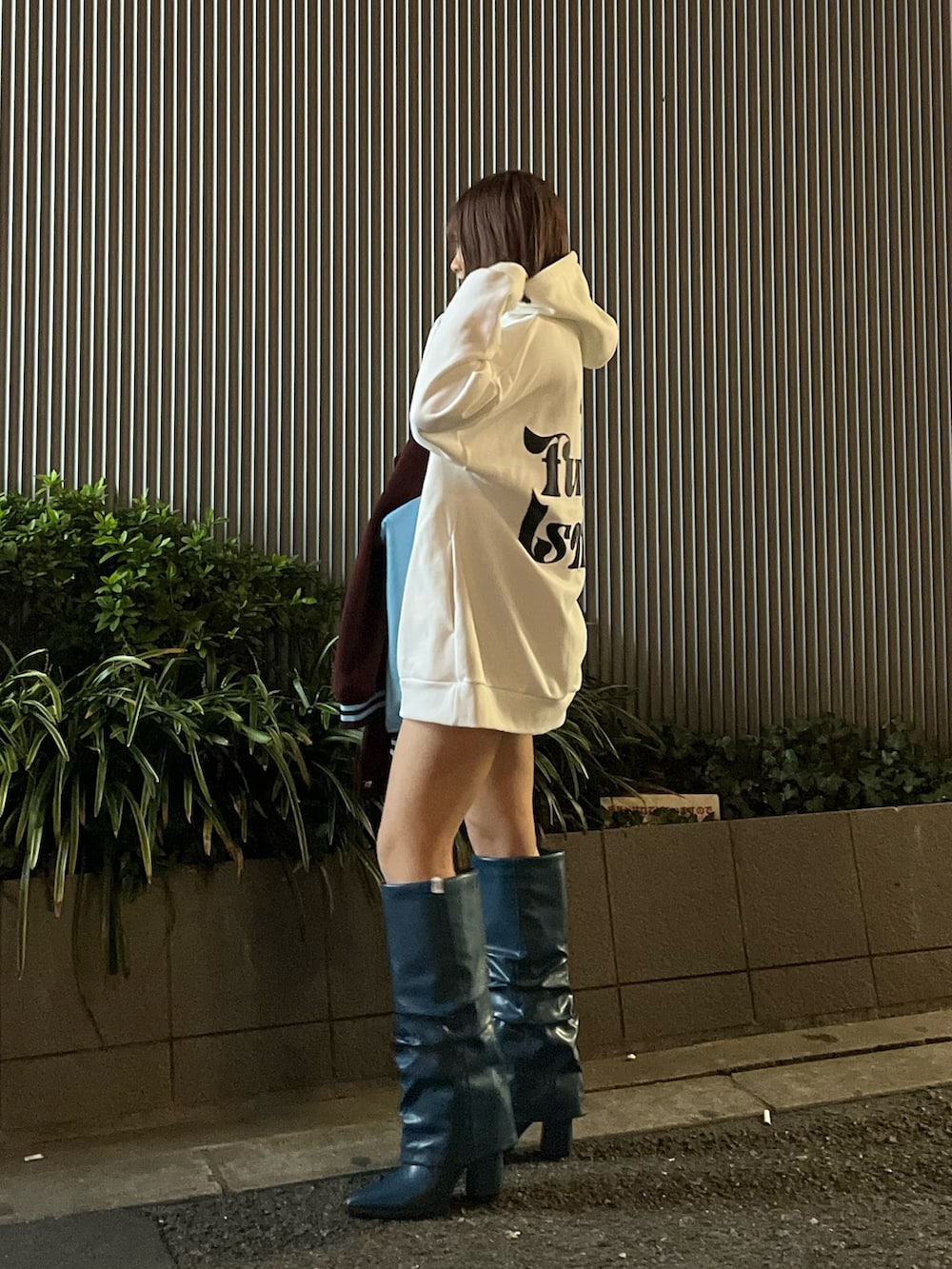 ブルー系のブーツ、レッド系のスタジャン、ホワイト系のパーカーを着用したレディースの冬コーディネートの3枚目の写真