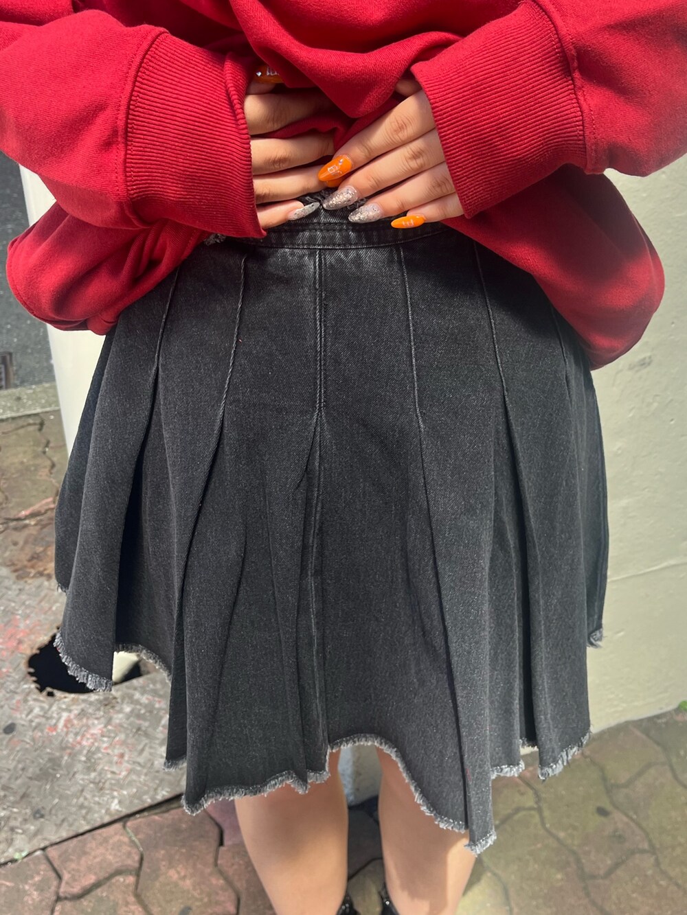 ブラック系のデニムスカート、レッド系のスウェット、ブラック系のブーツを着用したレディースの秋コーディネートの8枚目の写真