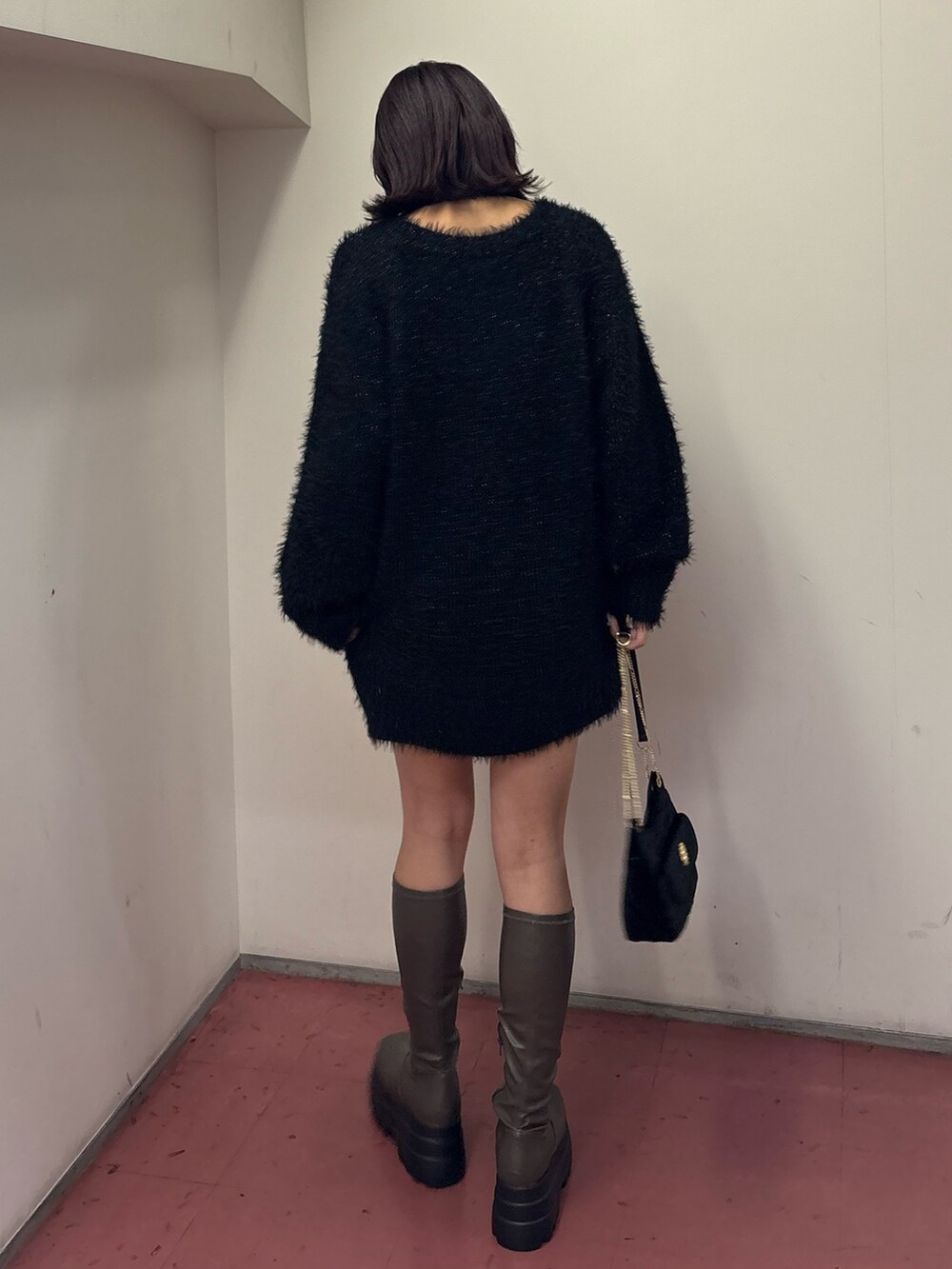 ブラック系のワンピース、ブラック系のショルダーバッグ、グリーン系のブーツを着用したレディースの冬コーディネートの3枚目の写真