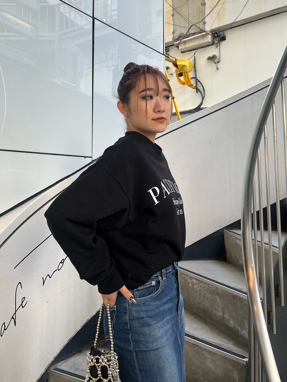 ブラック系のブーツ、ブラック系のスウェット、ブルー系のデニムスカートを着用したレディースの冬コーディネートの3枚目の写真