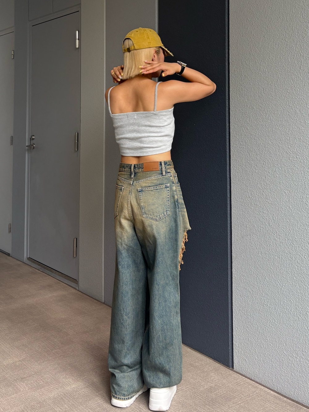 グレー系のワンピース、ブルー系のデニムパンツ、イエロー系のキャップを着用したレディースの夏コーディネートの3枚目の写真