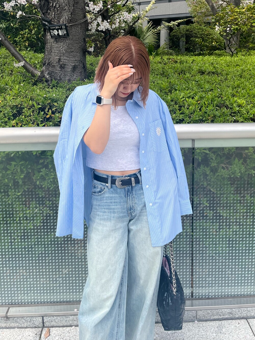 ブラック系のショルダーバッグ、ブルー系のシャツ/ブラウス、ブルー系のデニムパンツを着用したレディースの春コーディネートの5枚目の写真