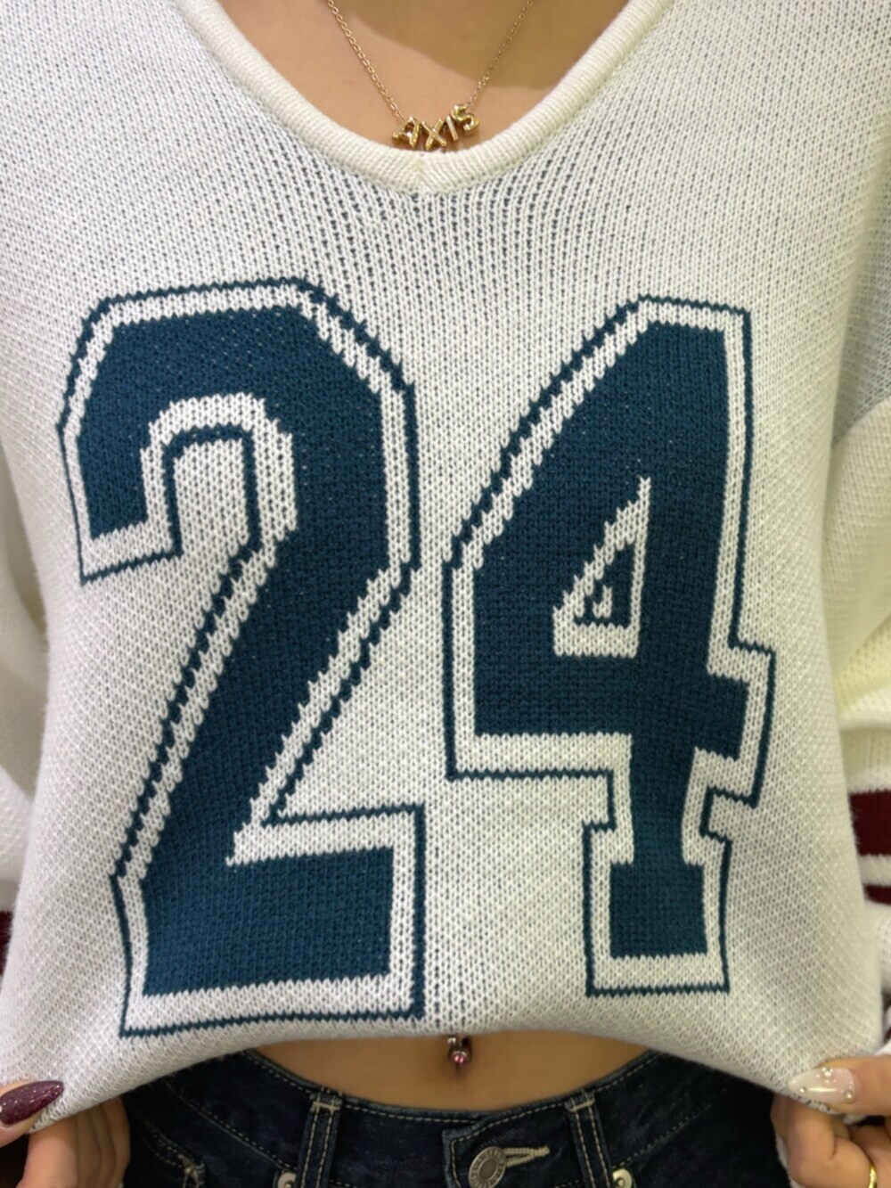 ブルー系のデニムパンツ、ブラウン系のハンドバッグ、ホワイト系のニット/セーターを着用したレディースの冬コーディネートの5枚目の写真