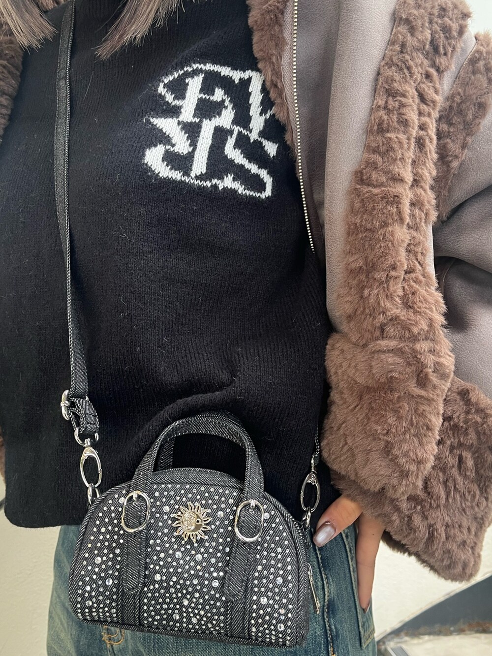 ブラウン系のムートンコート、ホワイト系のニット/セーター、ブルー系のデニムパンツを着用したレディースの冬コーディネートの5枚目の写真