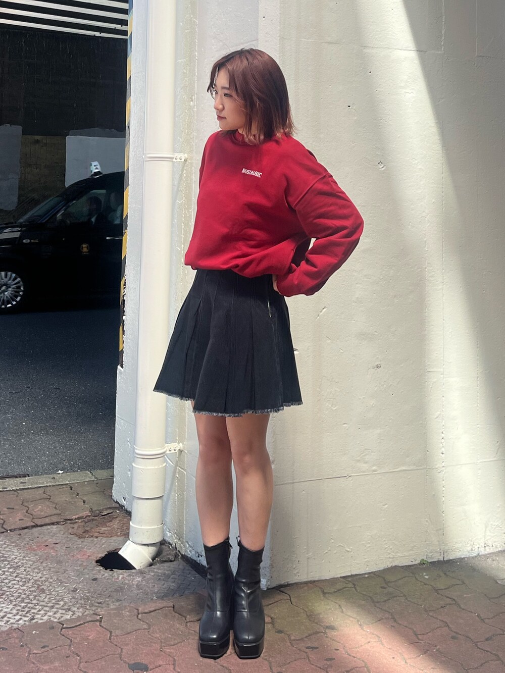 ブラック系のデニムスカート、レッド系のスウェット、ブラック系のブーツを着用したレディースの秋コーディネートの4枚目の写真