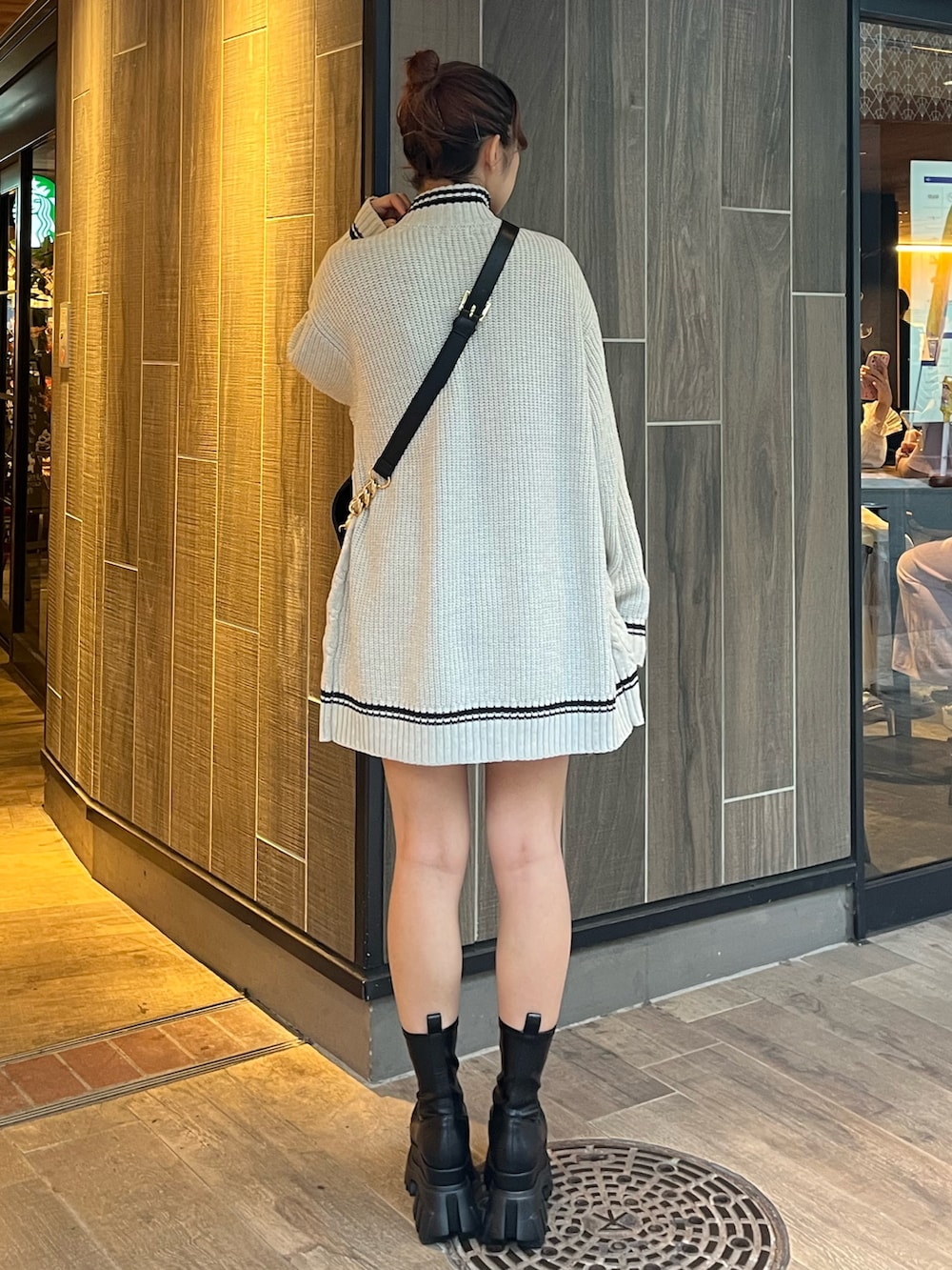 グレー系のニット/セーター、ブラック系のショルダーバッグ、ブラック系のブーツを着用したレディースの秋コーディネートの5枚目の写真