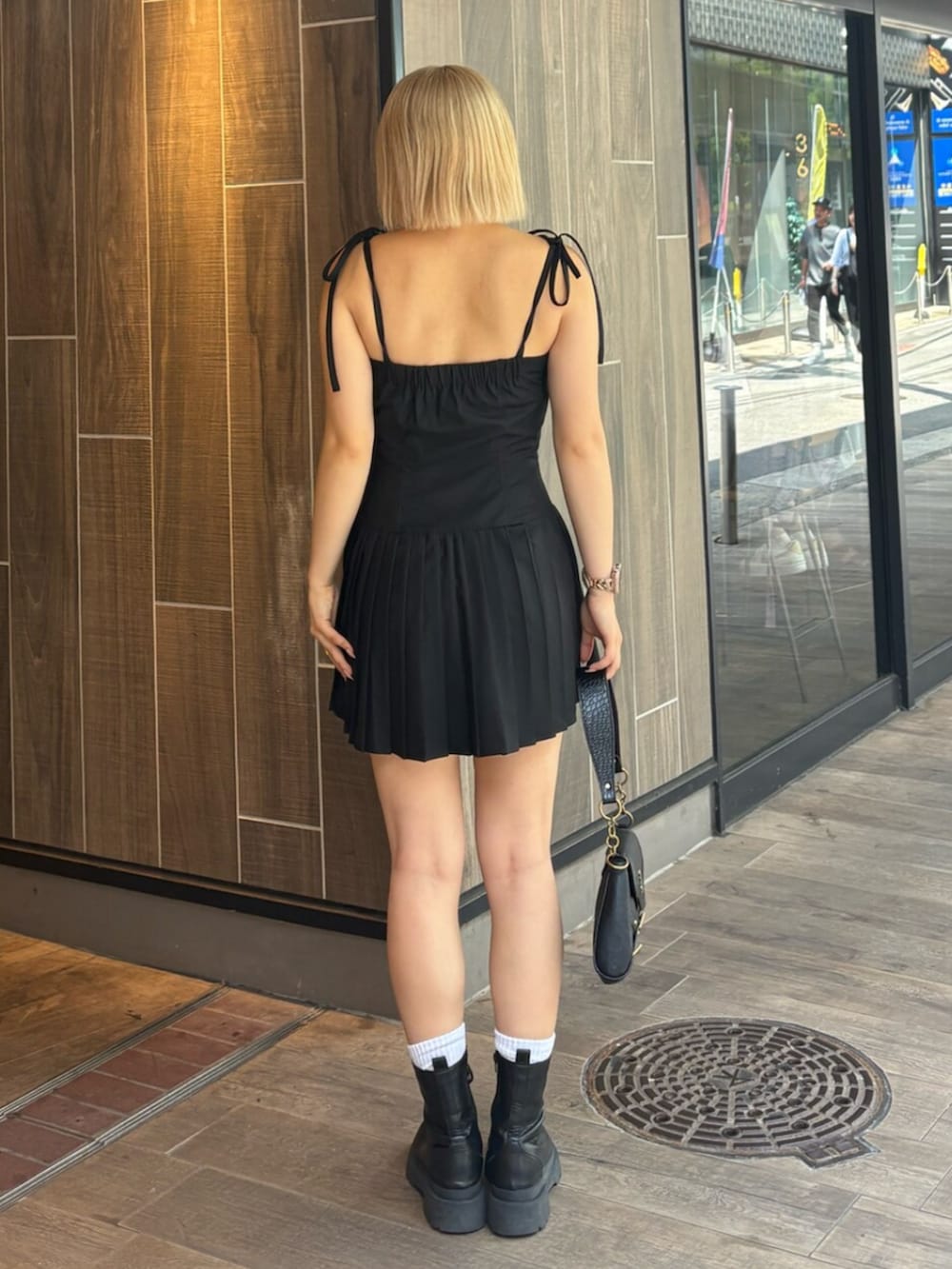 ブラック系のブーツ、ブラック系のワンピース、ブラック系のハンドバッグを着用したレディースの夏コーディネートの3枚目の写真