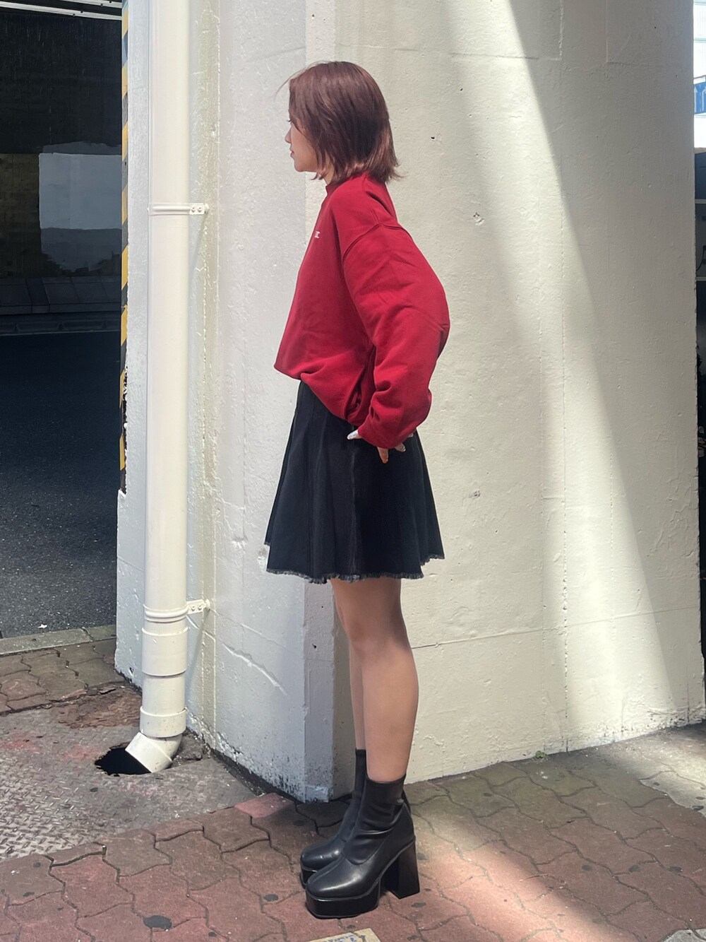 ブラック系のデニムスカート、レッド系のスウェット、ブラック系のブーツを着用したレディースの秋コーディネートの2枚目の写真