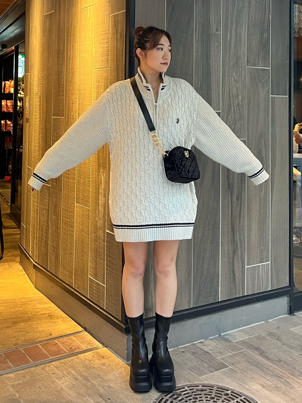 グレー系のニット/セーター、ブラック系のショルダーバッグ、ブラック系のブーツを着用したレディースの秋コーディネートの2枚目の写真