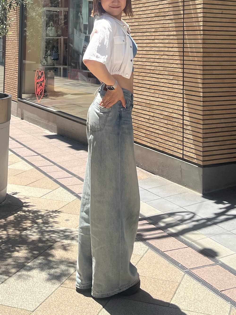 ブルー系のデニムパンツ、ブラック系のサンダル、ブルー系のキャミソールを着用したレディースの夏コーディネートの3枚目の写真