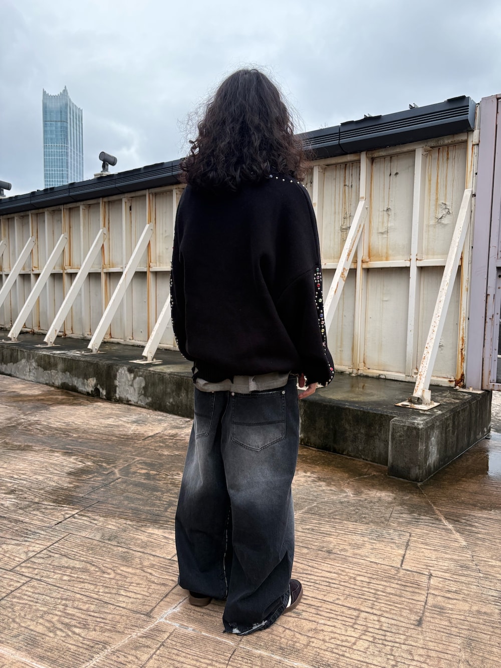 ブラック系のカーディガン/ボレロ、ベージュ系のTシャツ/カットソー、ブラック系のデニムパンツを着用したメンズの秋コーディネートの2枚目の写真