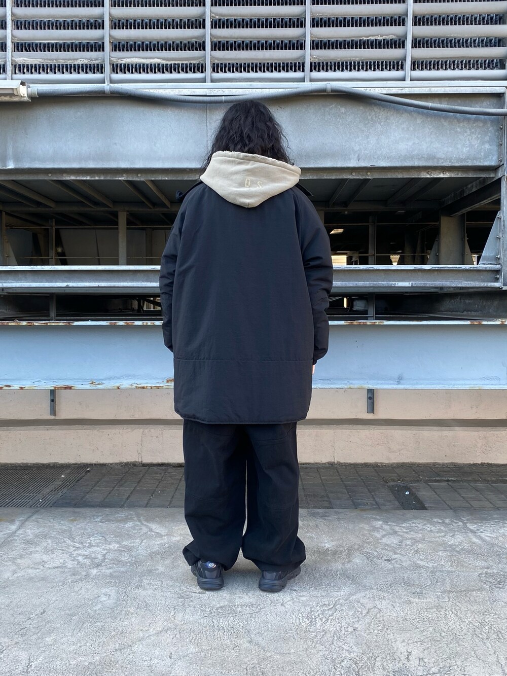 ベージュ系のパーカー、ブラック系のカーゴパンツ、ブラック系のマウンテンパーカーを着用したメンズの冬コーディネートの2枚目の写真