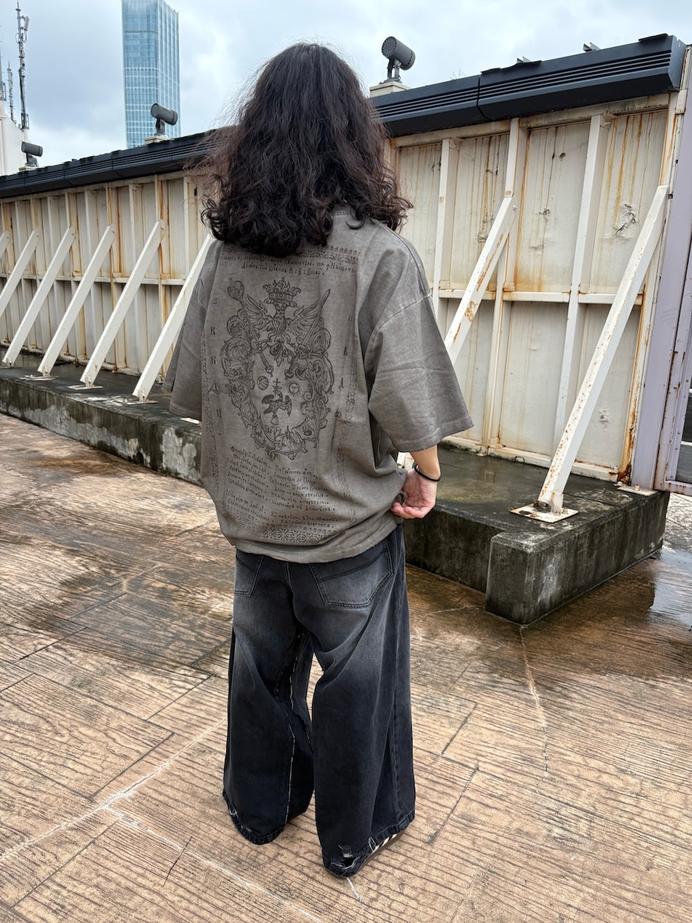 ブラック系のカーディガン/ボレロ、ベージュ系のTシャツ/カットソー、ブラック系のデニムパンツを着用したメンズの秋コーディネートの6枚目の写真