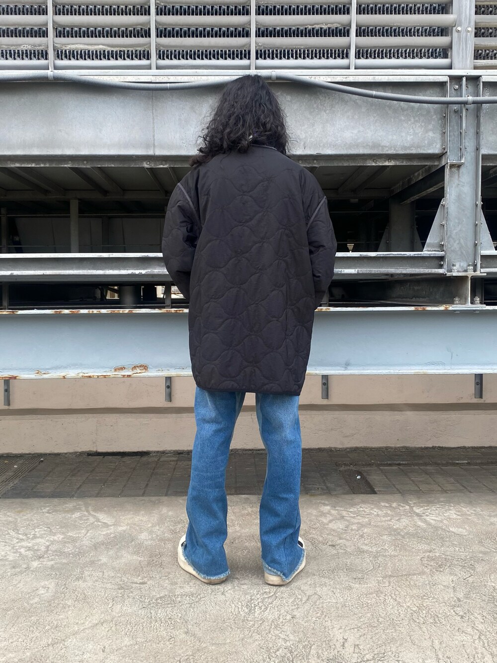 ブラック系のその他アウター、グレー系のTシャツ/カットソー、ブルー系のデニムパンツを着用したメンズの冬コーディネートの2枚目の写真