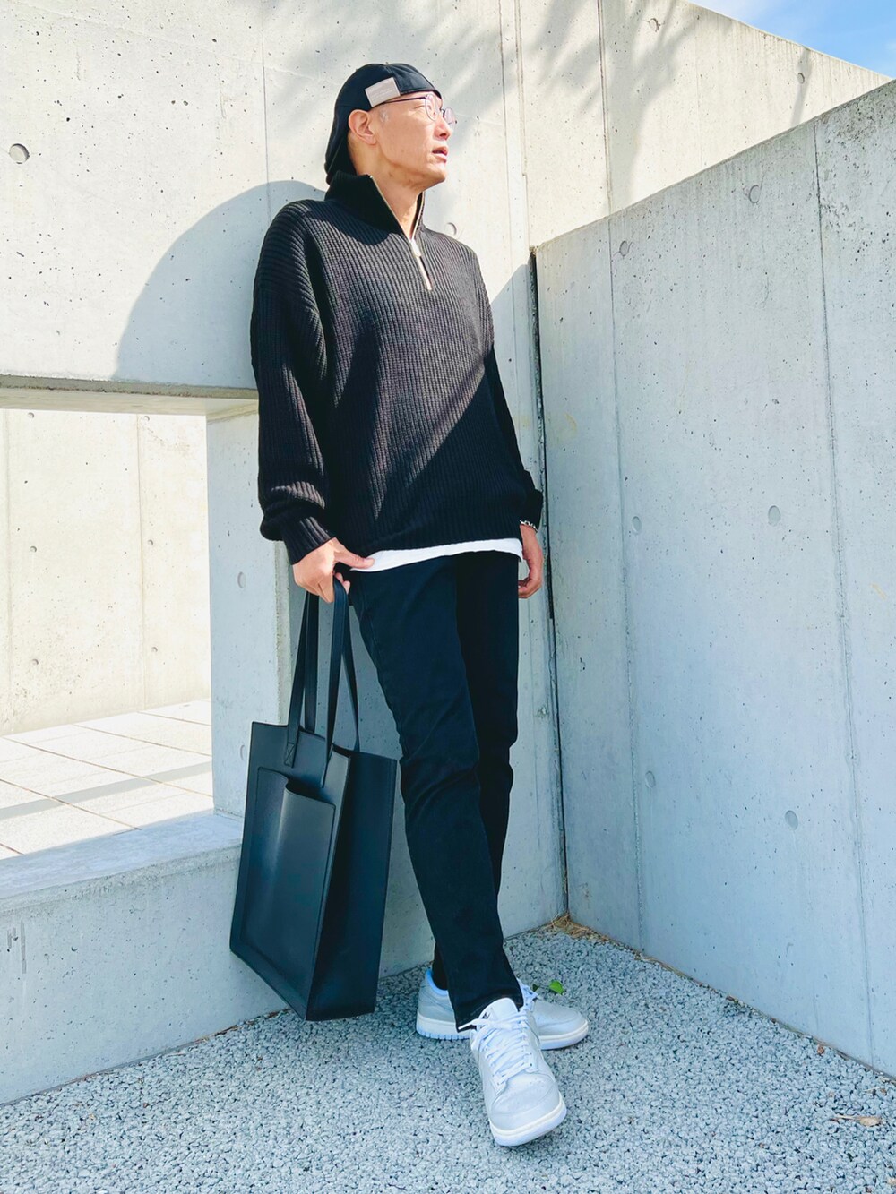 ブラック系のデニムパンツ、ブラック系のニット/セーター、ブラック系のトートバッグを着用したメンズの秋コーディネートの3枚目の写真