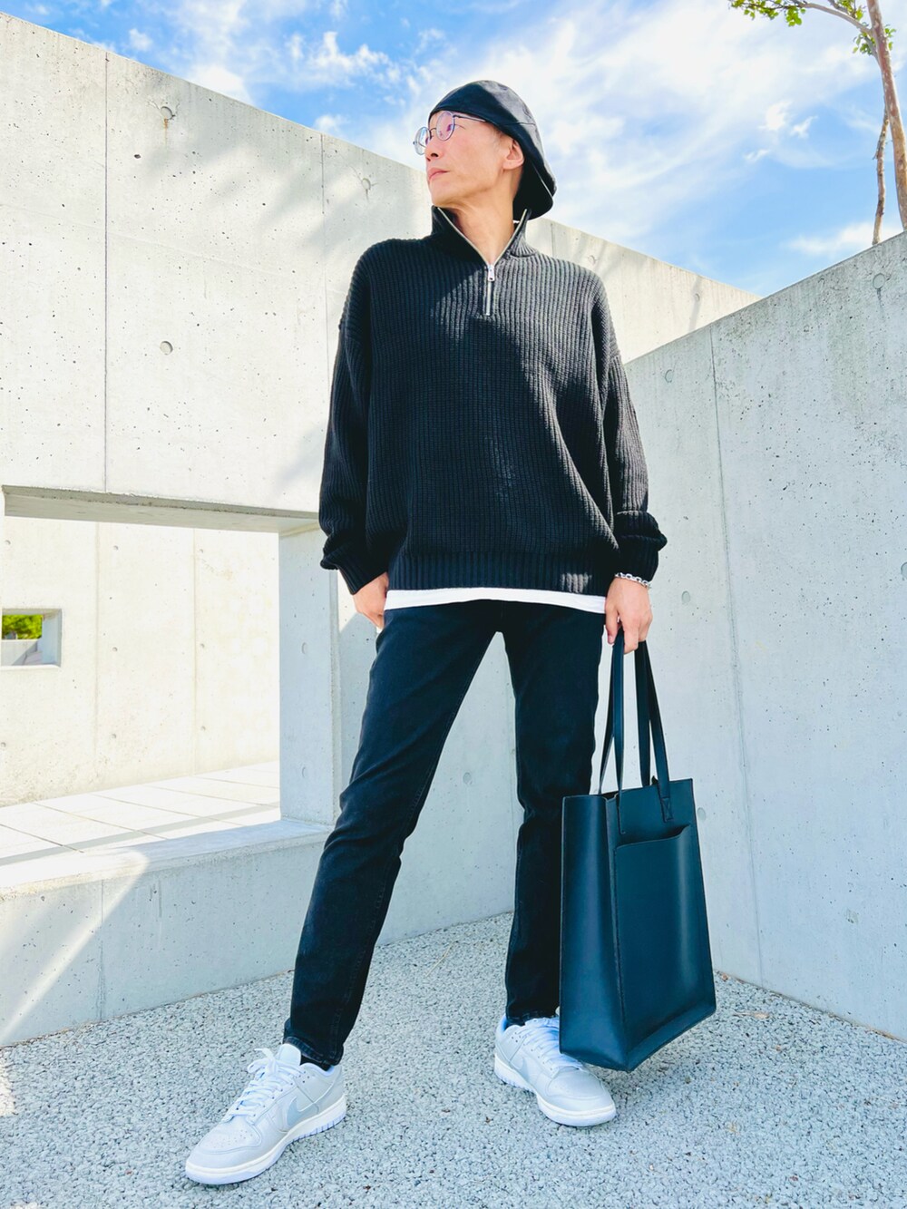 ブラック系のデニムパンツ、ブラック系のニット/セーター、ブラック系のトートバッグを着用したメンズの秋コーディネートの2枚目の写真