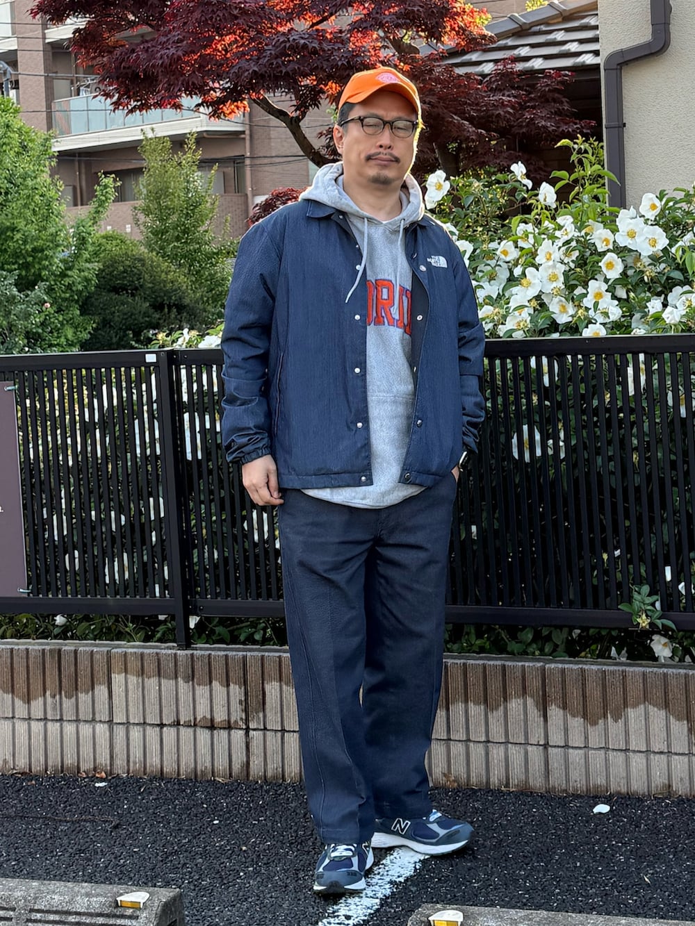 グレー系のパーカー、ブルー系のナイロンジャケット、ブルー系のチノパンツを着用したメンズの春コーディネートの4枚目の写真