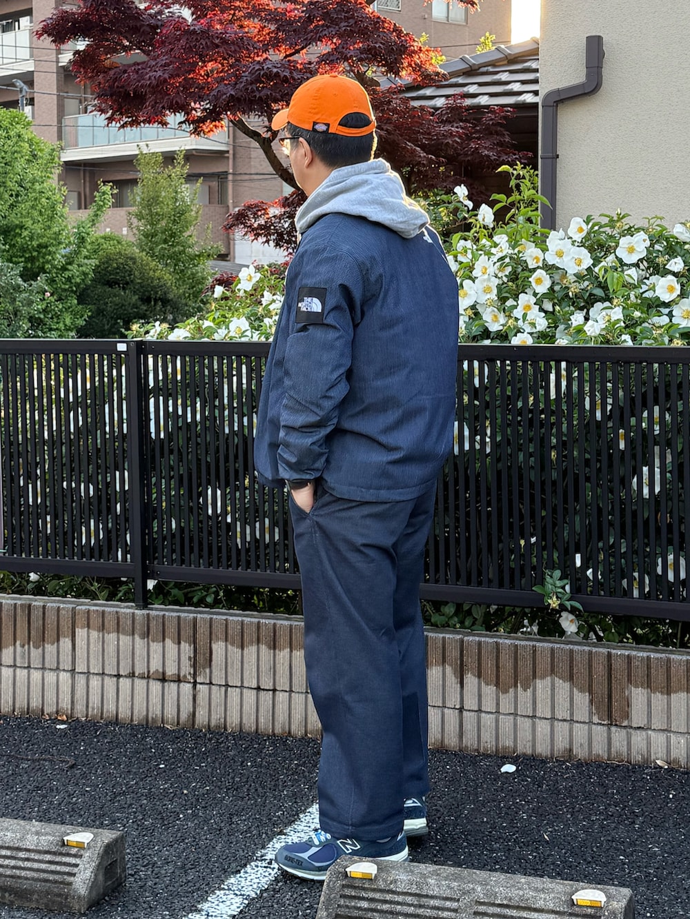 グレー系のパーカー、ブルー系のナイロンジャケット、ブルー系のチノパンツを着用したメンズの春コーディネートの2枚目の写真