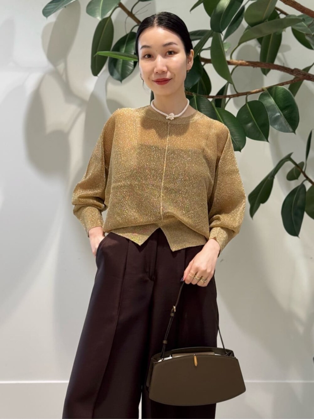 イエロー系のスラックス、グレー系のキャミソール、ゴールド系のニット/セーターを着用したレディースの夏コーディネートの2枚目の写真