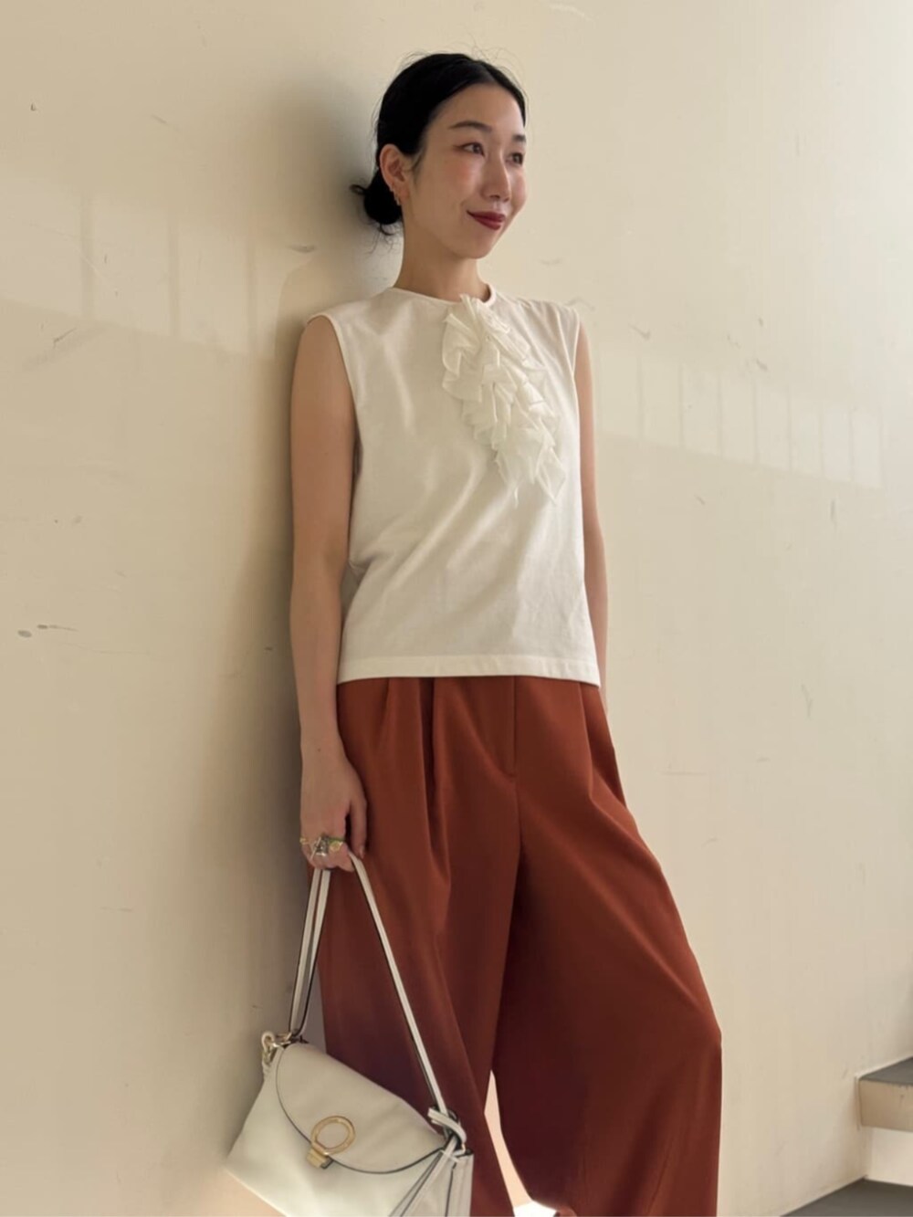 ホワイト系のキャミソール、ホワイト系のショルダーバッグ、イエロー系のスラックスを着用したレディースの夏コーディネートの2枚目の写真