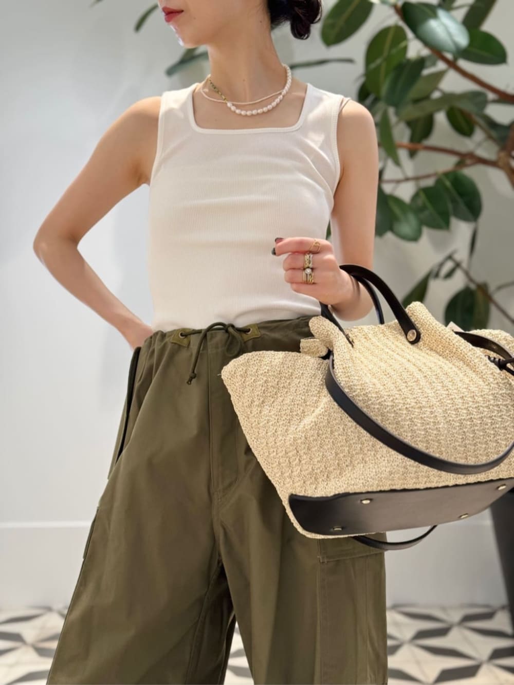 ホワイト系のタンクトップ、ベージュ系のかごバッグ、ホワイト系のキャミソールを着用したレディースの夏コーディネートの3枚目の写真