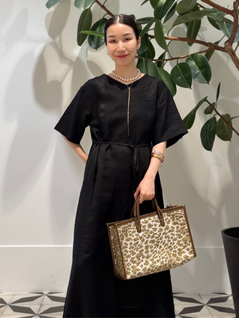 ブラック系のキャミソール、ベージュ系のトートバッグ、ブラック系のワンピースを着用したレディースの夏コーディネートの2枚目の写真