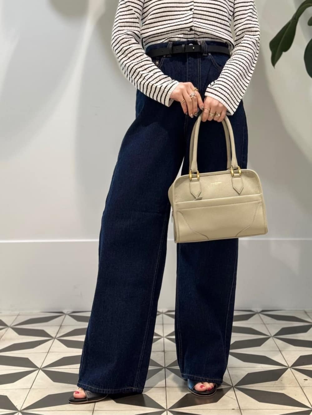 ホワイト系のキャミソール、ブラック系のサンダル、ブルー系のデニムパンツを着用したレディースの夏コーディネートの3枚目の写真