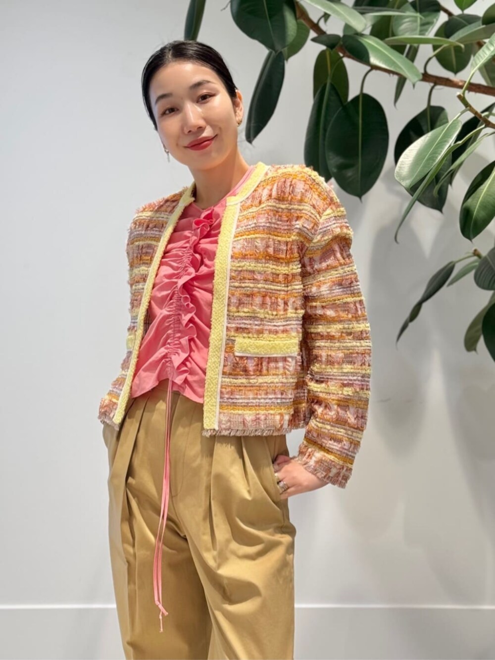 ベージュ系のチノパンツ、イエロー系のハンドバッグ、オレンジ系のカーディガン/ボレロを着用したレディースの春コーディネートの2枚目の写真