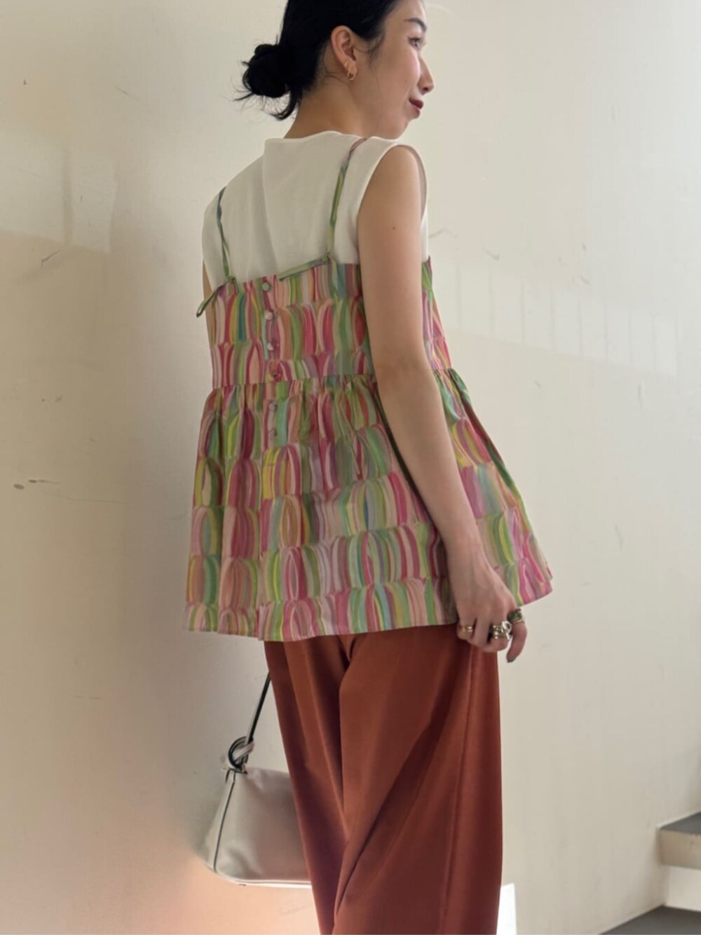 ホワイト系のキャミソール、ホワイト系のショルダーバッグ、イエロー系のスラックスを着用したレディースの夏コーディネートの5枚目の写真