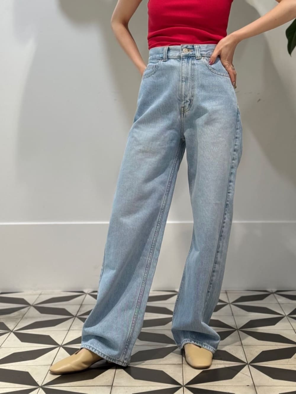 ブルー系のデニムパンツ、ベージュ系のパンプス、レッド系のタンクトップを着用したレディースの夏コーディネートの4枚目の写真