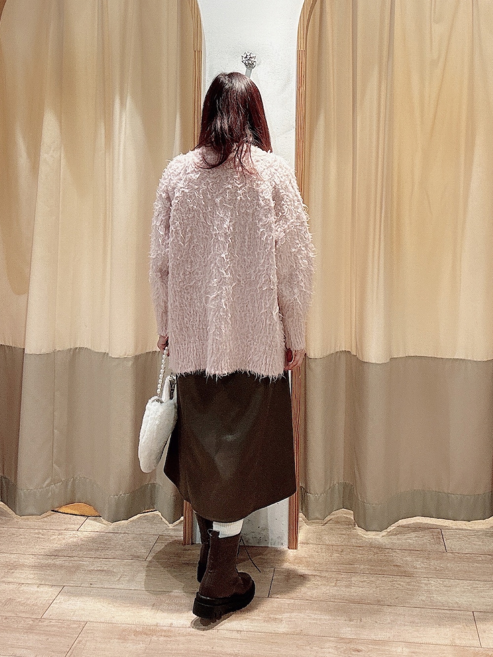 ピンク系のカーディガン/ボレロ、ブラウン系のワンピース、ホワイト系のハンドバッグを着用したレディースの秋コーディネートの2枚目の写真