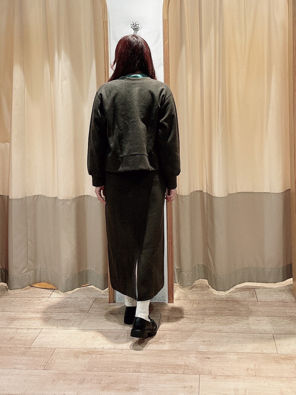 グリーン系のニット/セーター、ブラウン系のカーディガン/ボレロ、ブラウン系のスカートを着用したレディースの冬コーディネートの2枚目の写真