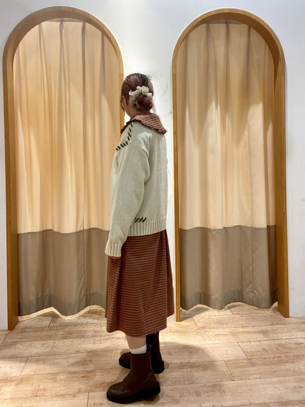 レッド系のワンピース、ホワイト系のニット/セーター、ブラウン系のブーツを着用したレディースの秋コーディネートの2枚目の写真