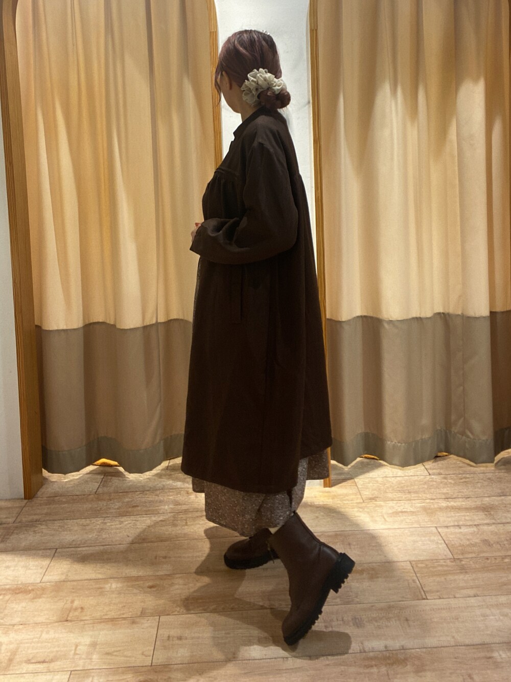 レッド系のワンピース、ブラウン系のその他アウター、ブラウン系のブーツを着用したレディースの秋コーディネートの2枚目の写真